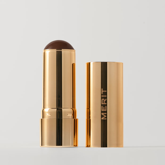 Master || A stick bronzer product by MERIT, with the cap off, showing the bronzing cream inside and MERIT on the cap.