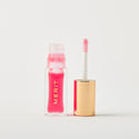Master || A bottle of Merit lip oil in shade Les Deux displayed next to its applicator. 