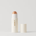 Master ||  A stick highlighter with the brand name MERIT written on it, with the product cap removed, revealing the highlighter balm in shade Citrine