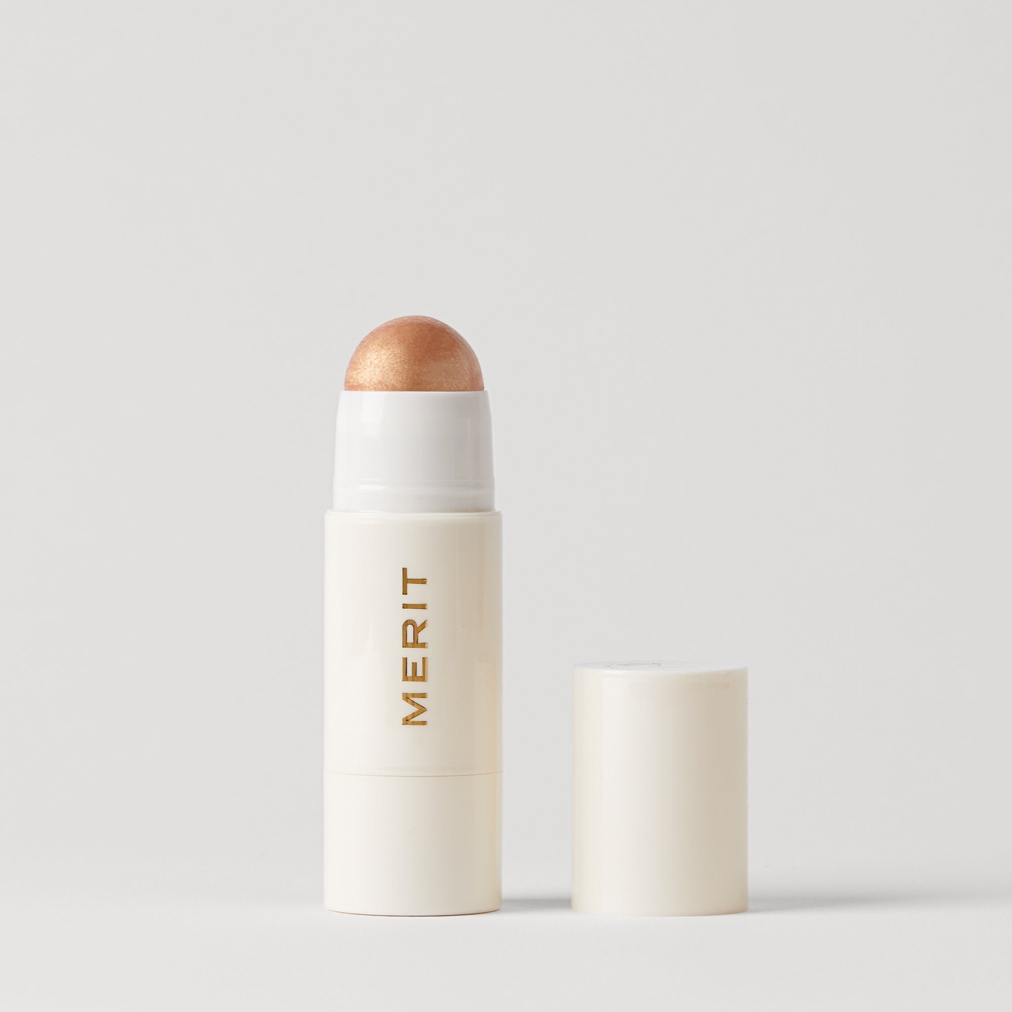 Master ||  A stick highlighter with the brand name MERIT written on it, with the product cap removed, revealing the highlighter balm in shade Citrine