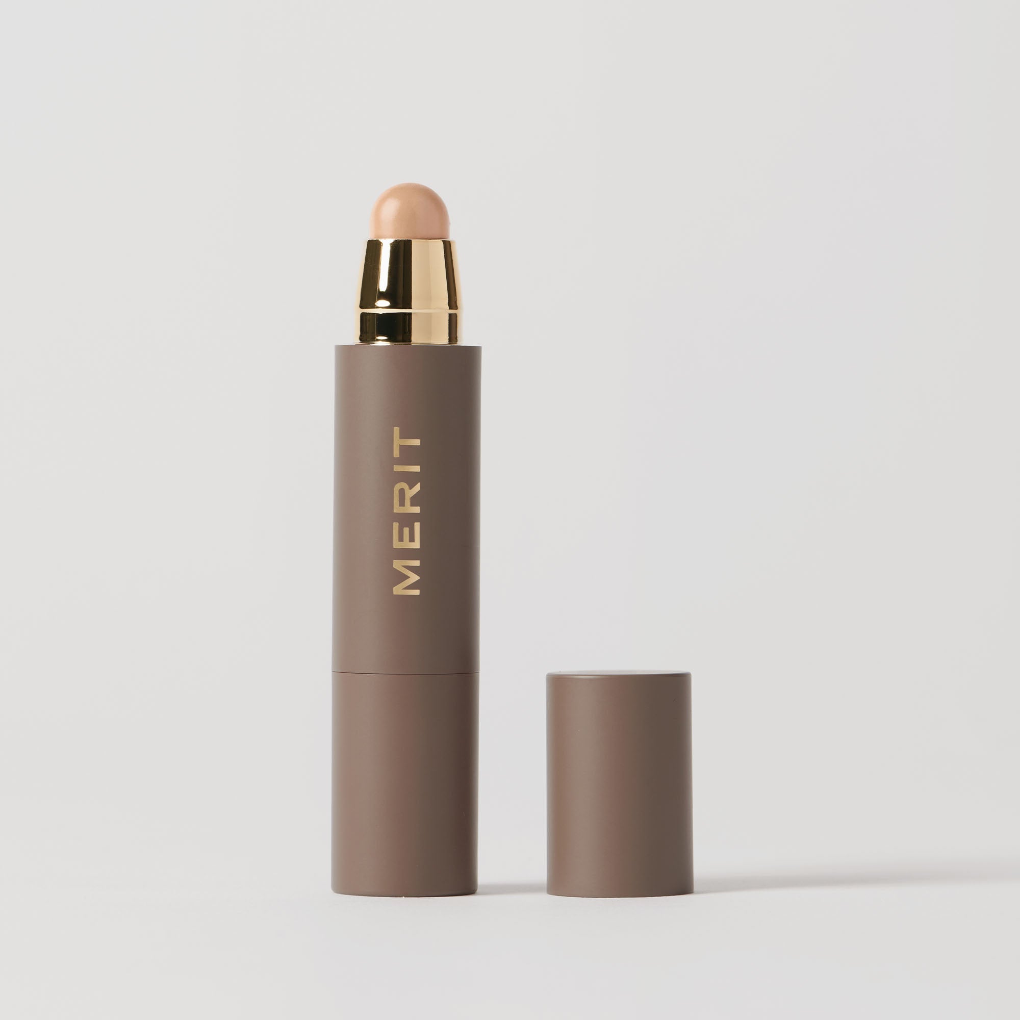 Master || A stick concealer product with the brand name 'MERIT' written on it, with the cap removed