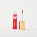 Master || A bottle of Merit lip oil in shade Maraschino displayed next to its applicator. 