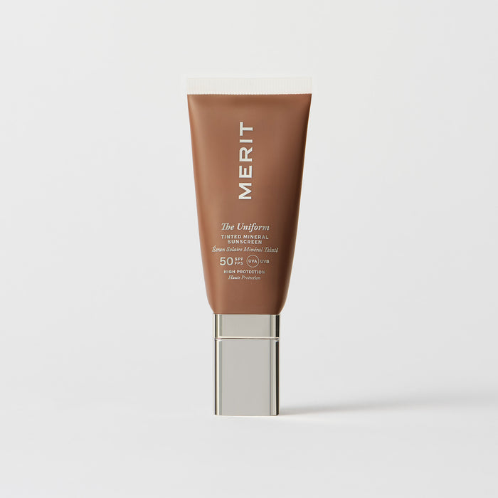 Master || A tube of MERIT brand mineral sunscreen with a sheer tint finish, providing broad spectrum 50 UVA/UVB protection, displayed against a white background.