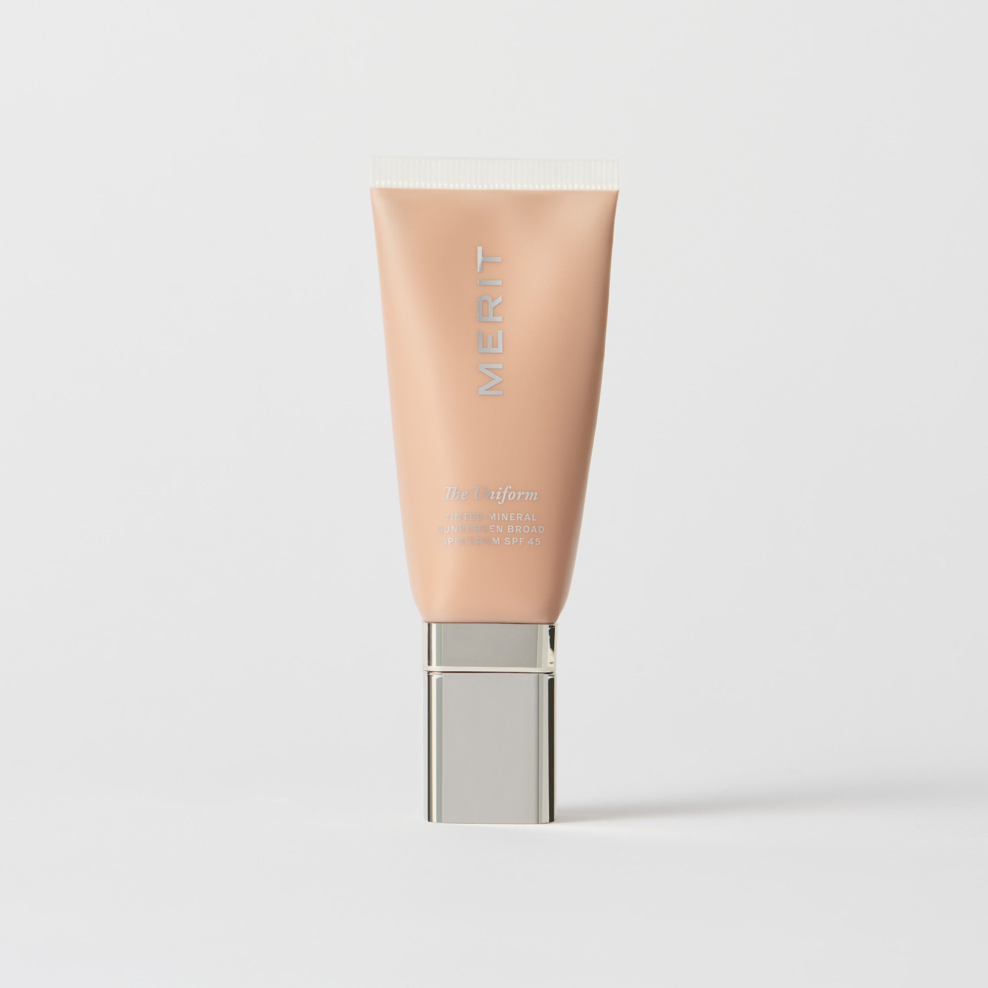 Master || A tube of MERIT brand mineral sunscreen with a sheer tint finish, providing broad spectrum 45 UVA/UVB protection, displayed against a white background.