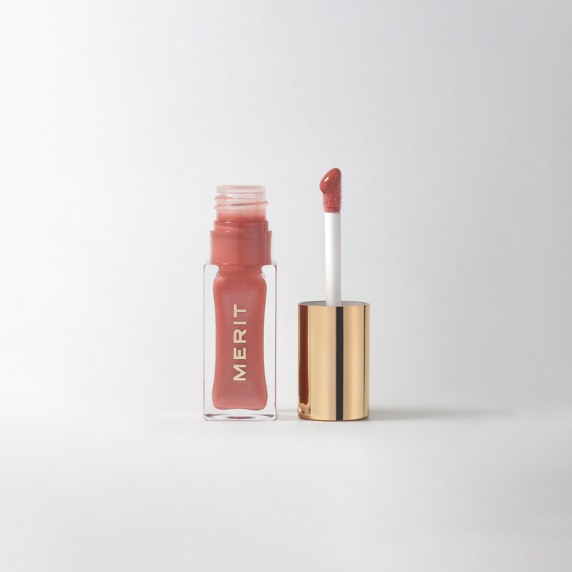 Master || A bottle of Merit lip oil in  shade Biarritz displayed next to its applicator. 