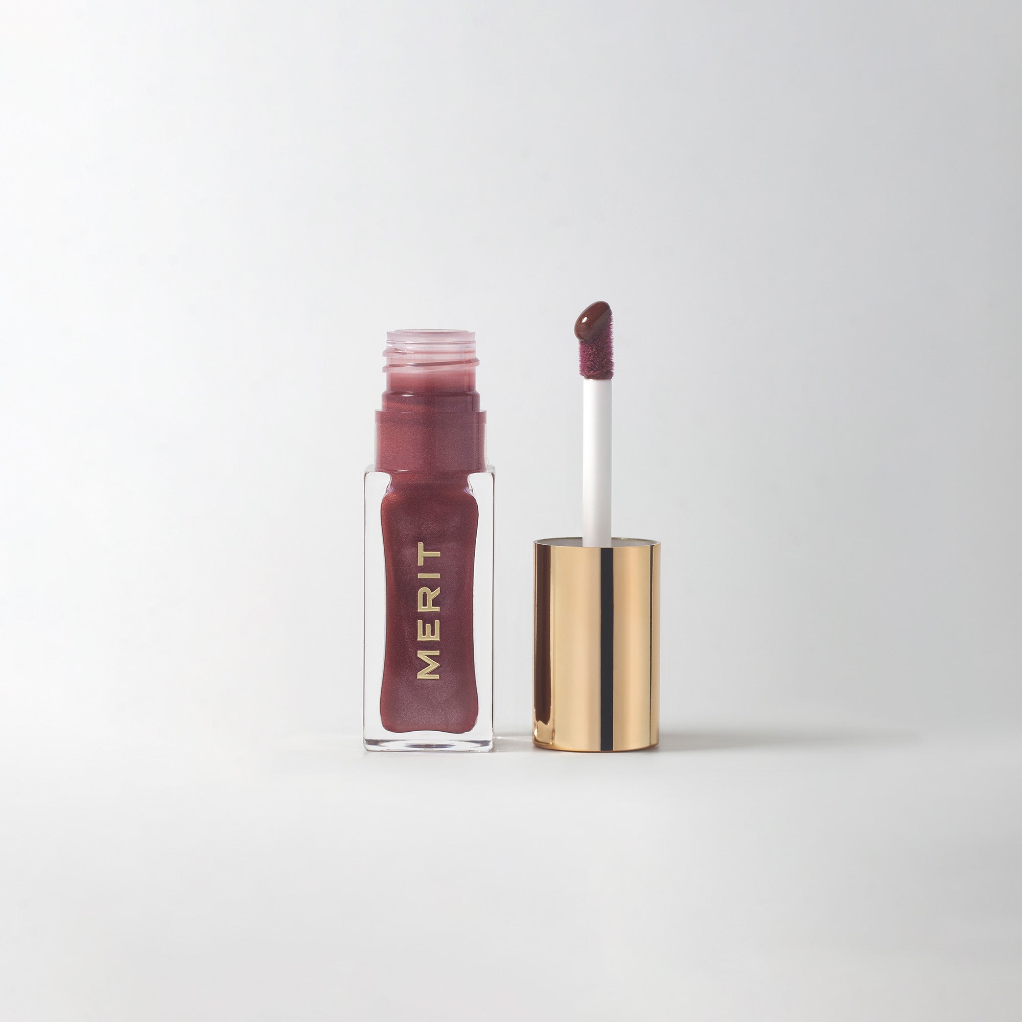Tabby | |  A bottle of Merit lip oil in  shade Tabby displayed next to its applicator. 