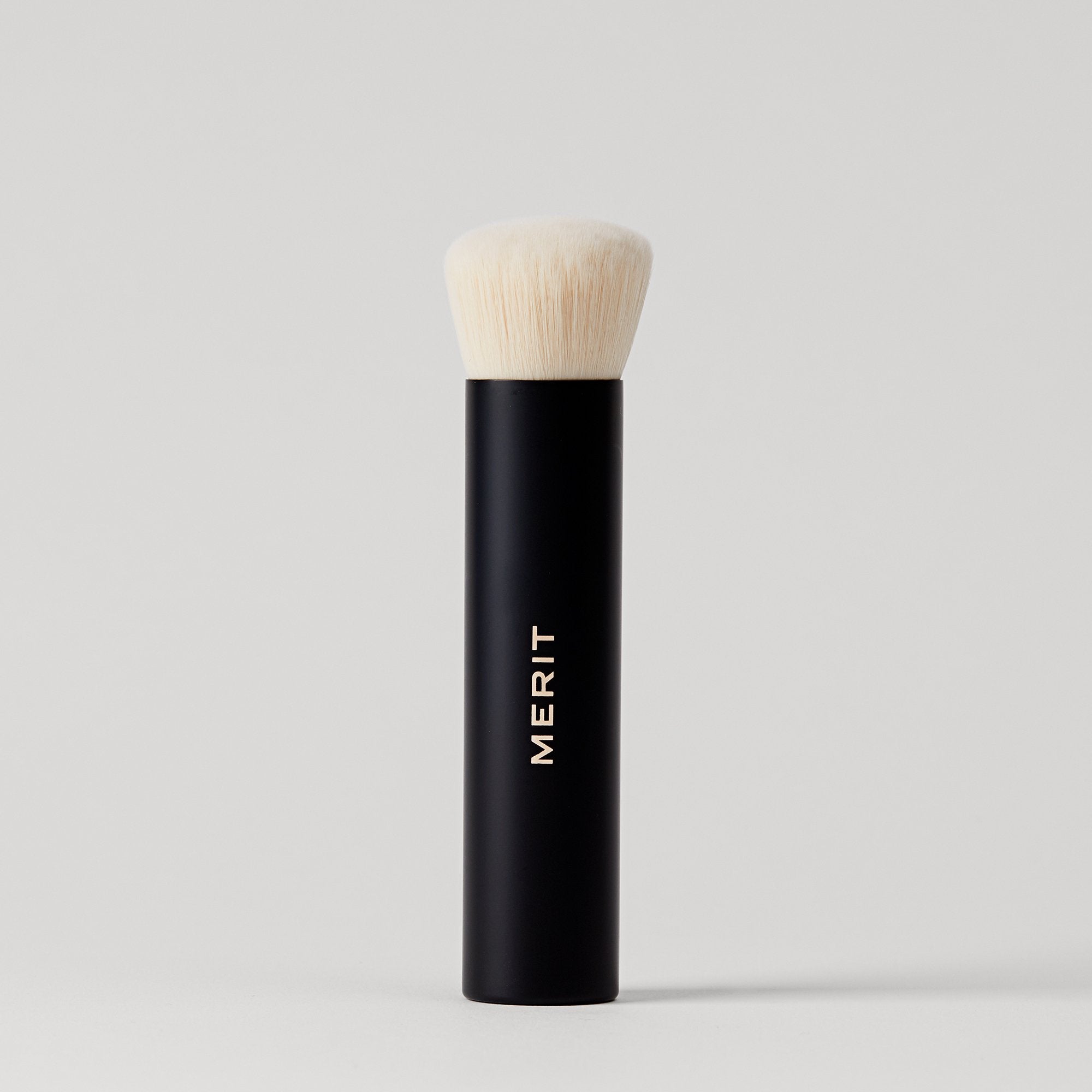 Master || A black makeup brush with a white bristle head, standing upright