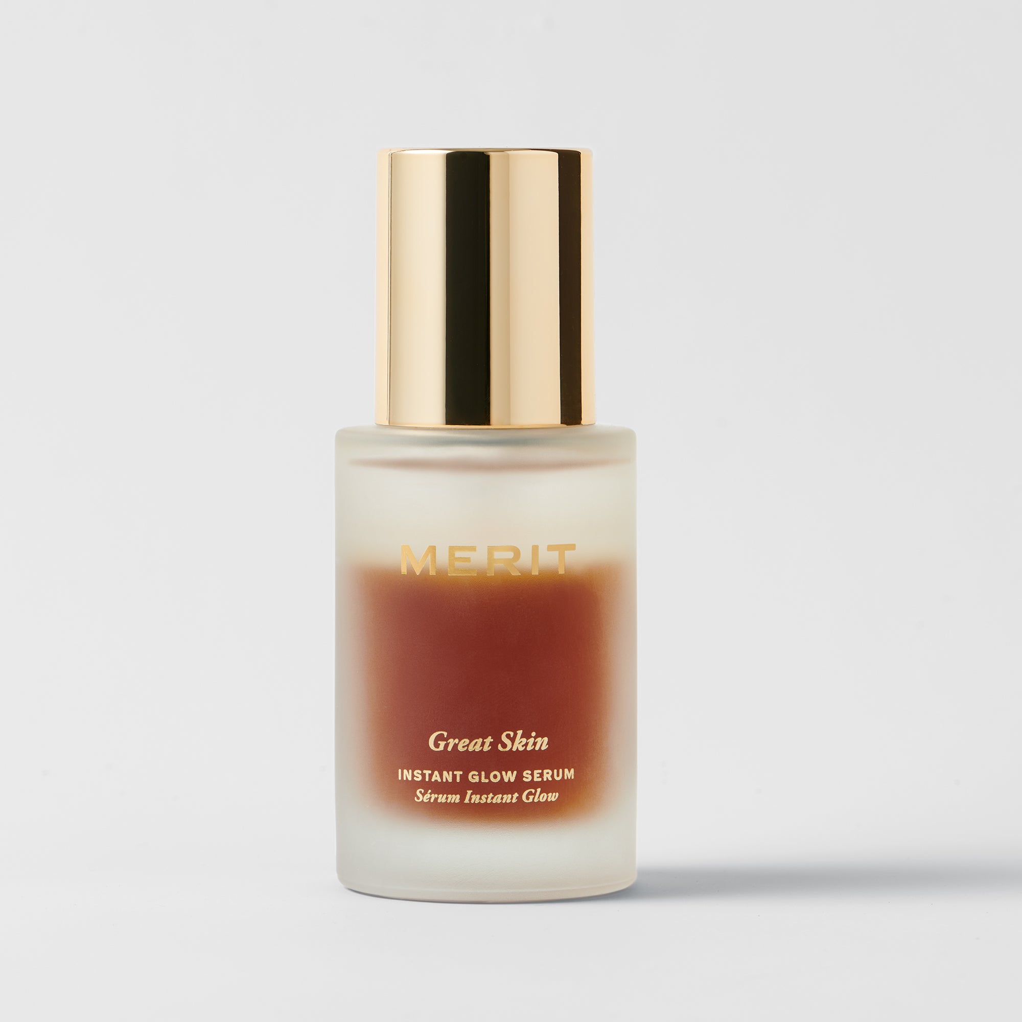 Master | |  skin care serum with dark and clear bi-phase liquid visible through the clear glass, branded 'MERIT', with a gold cap on the bottle.